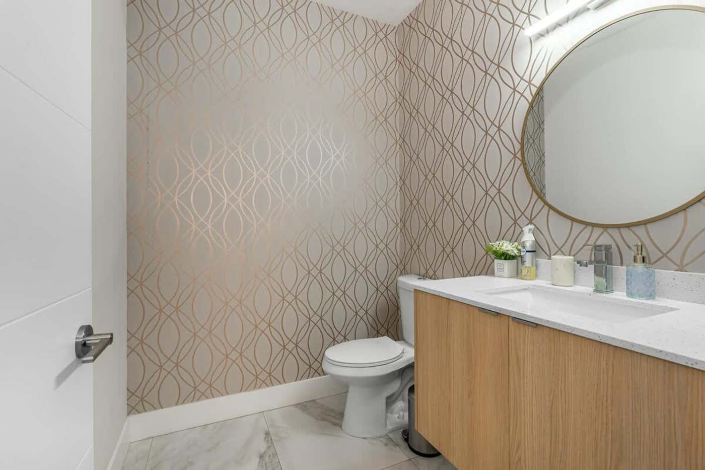 The Arcade House: Cloakroom with patterned wallpaper, vanity and a round mirror