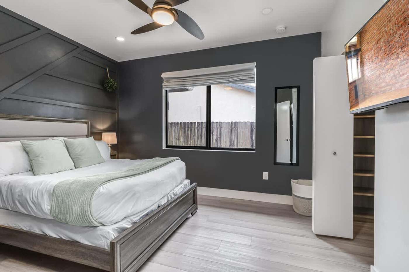 The Arcade House: Bedroom with king bed, dark feature wall and an ensuite