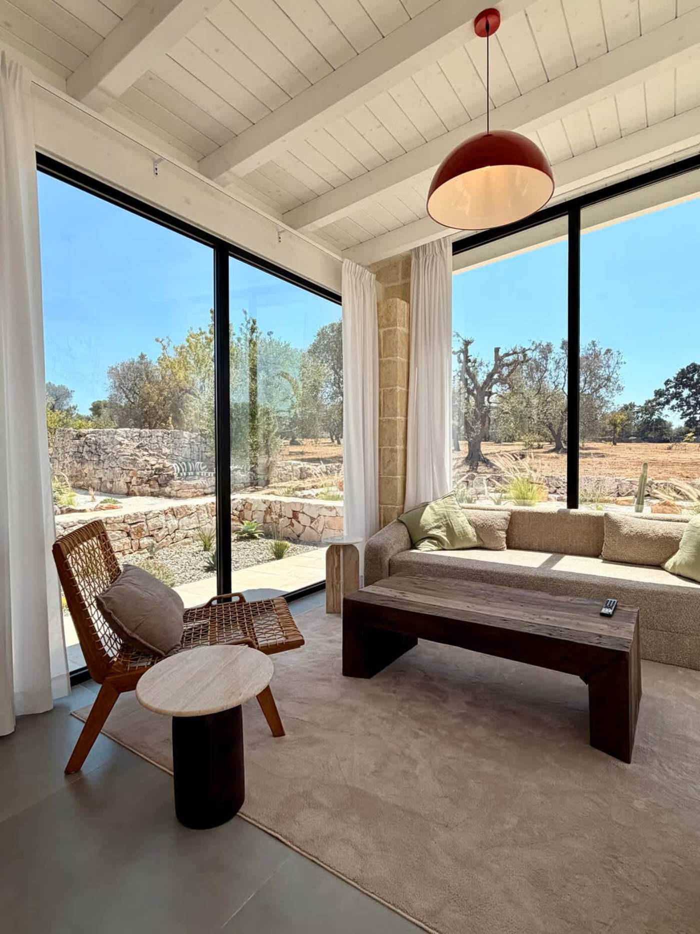 Trullo Ostro: Living room with sofa and wall-to-wall glass onto the olive grove