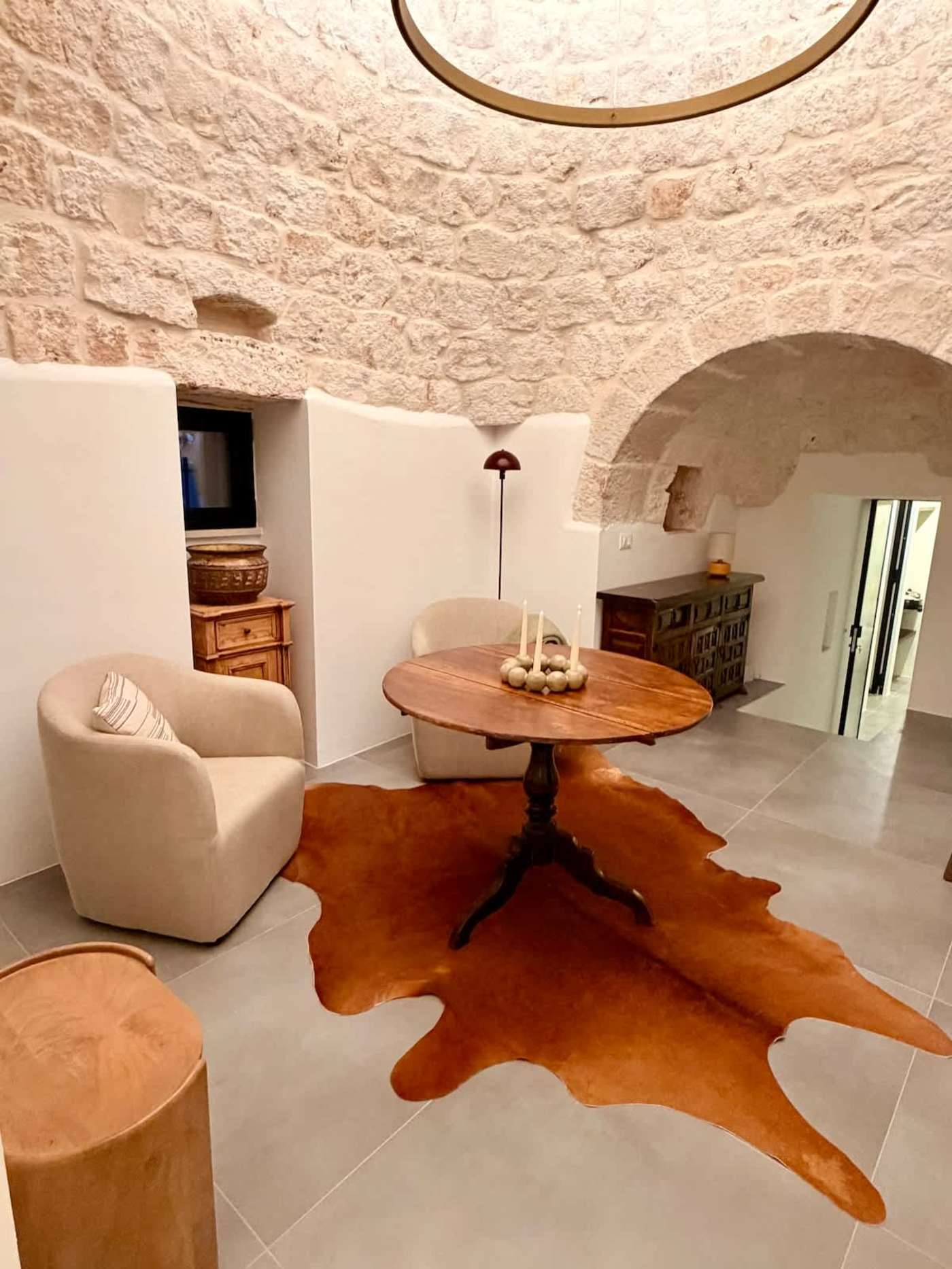 Trullo Ostro: Trullo sitting room with round table, armchairs and TV