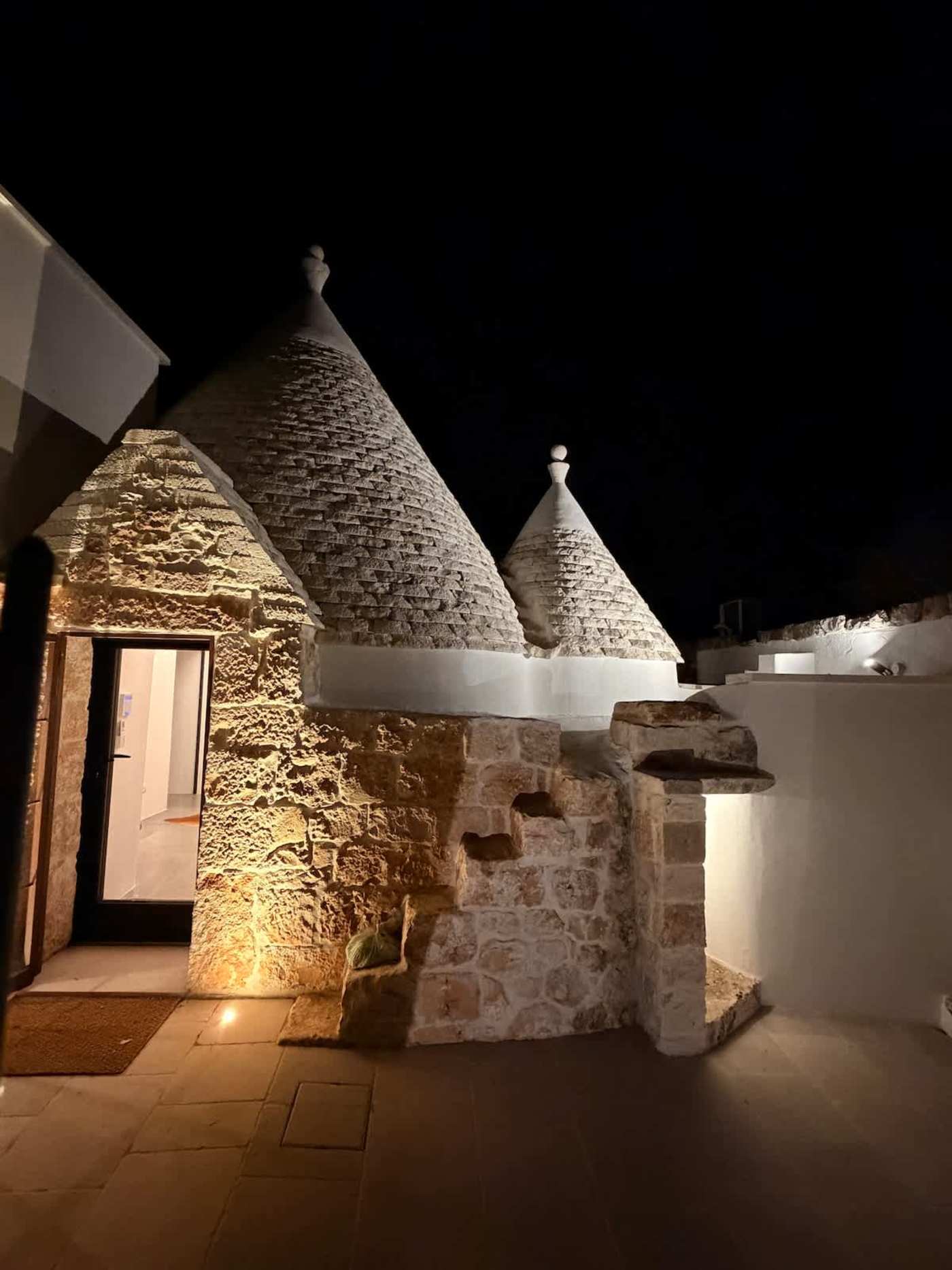 Trullo Ostro: Trullo entrance with lit stone walls at night