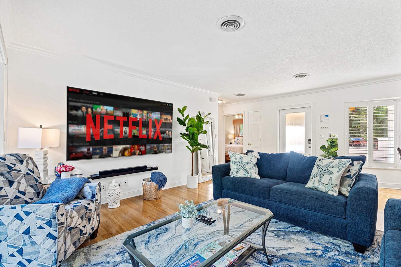 Cypress Cove: The living room has blue sofas, a glass coffee table and a large Smart TV