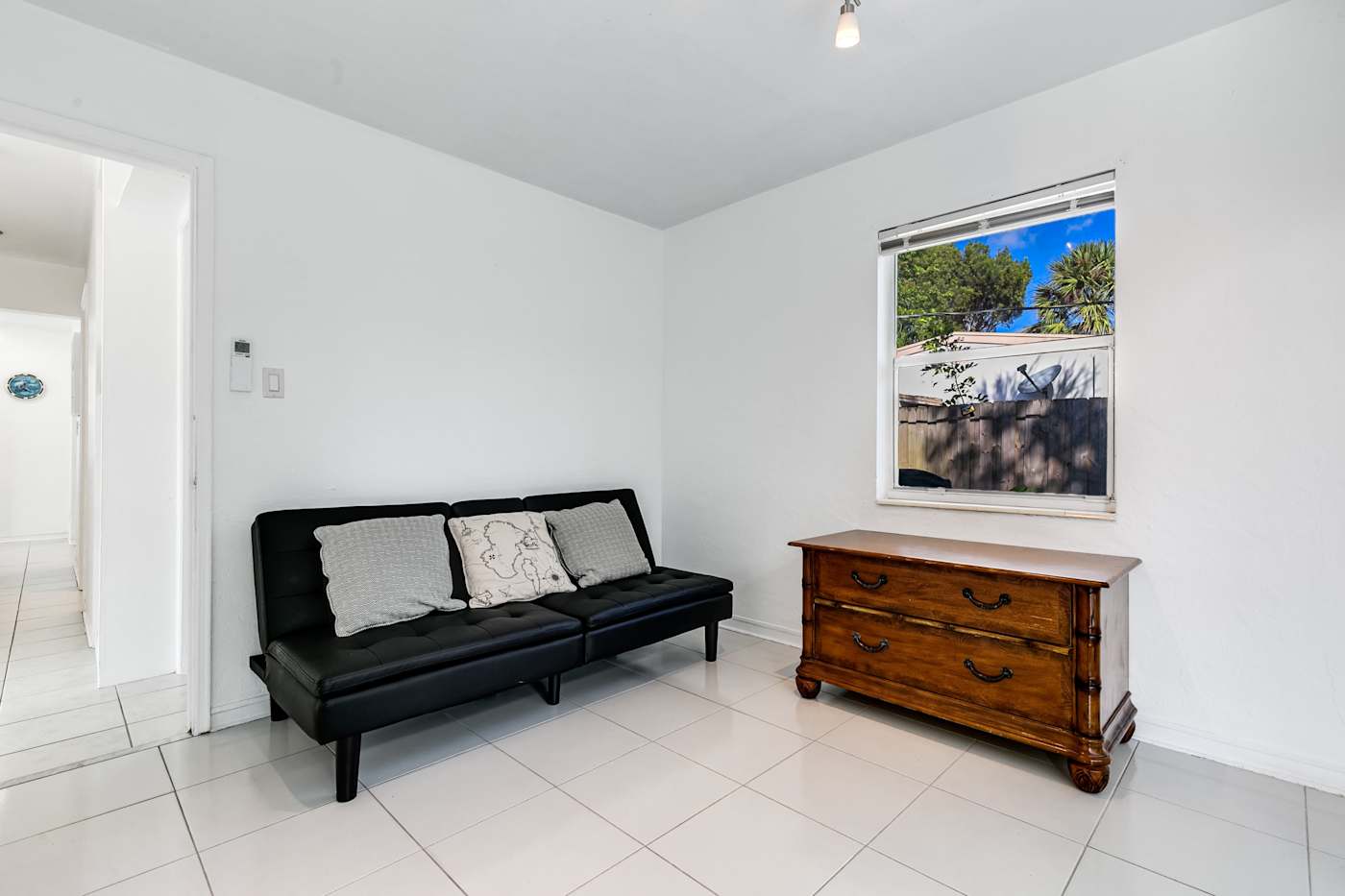 Pompano Bungalow: This room has a black sofa, a wood chest and a window