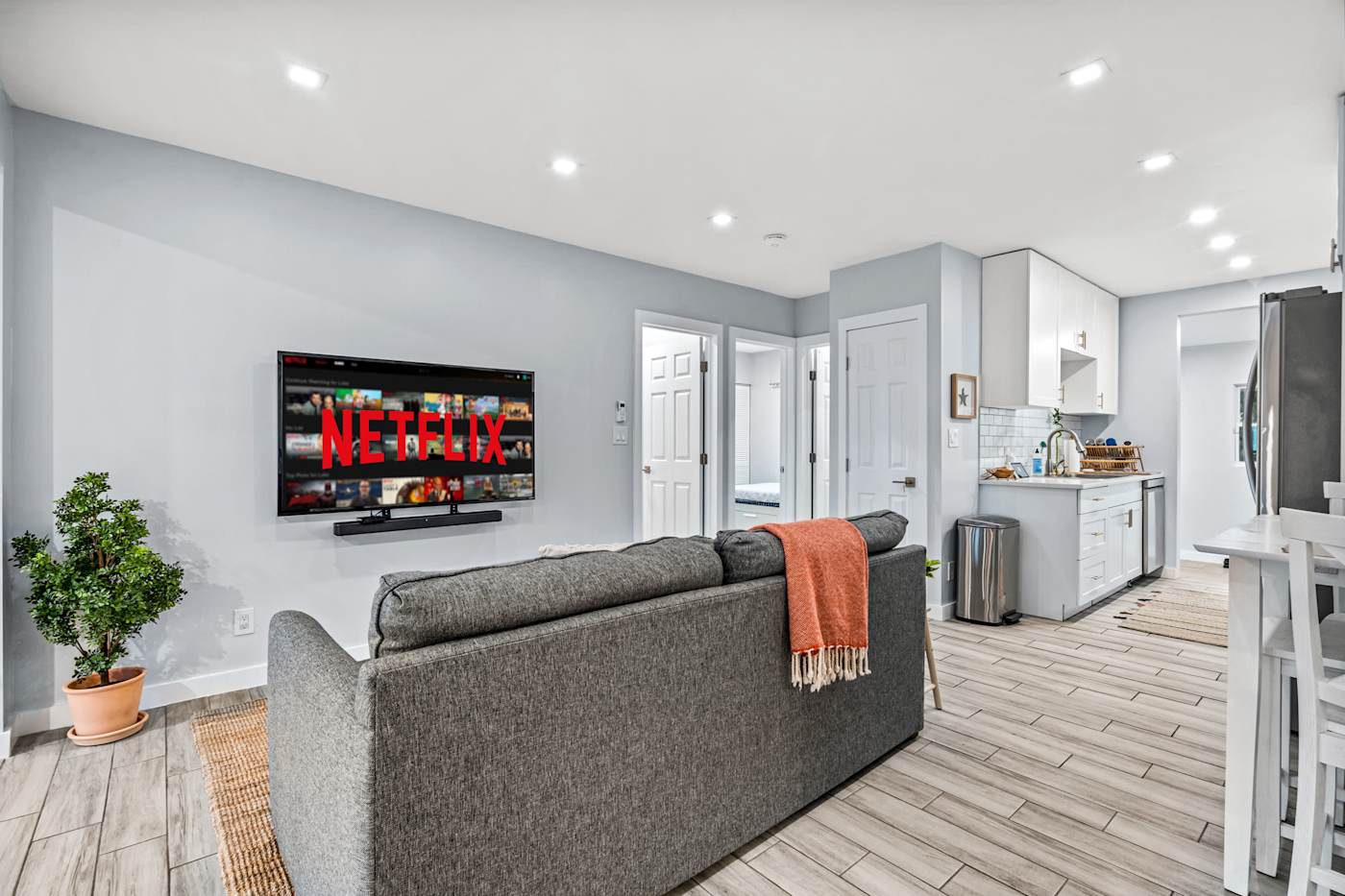 EV Retreat: The living room has a sofa and a wall-mounted Smart TV, open to the kitchen