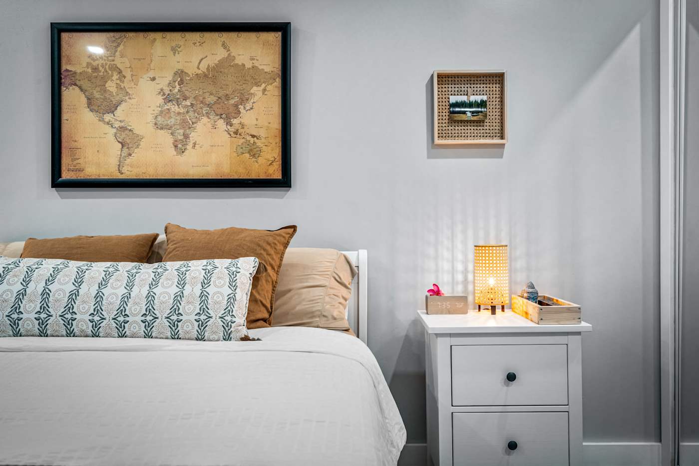 EV Retreat: A bed and nightstand with a lamp sit under a framed world map