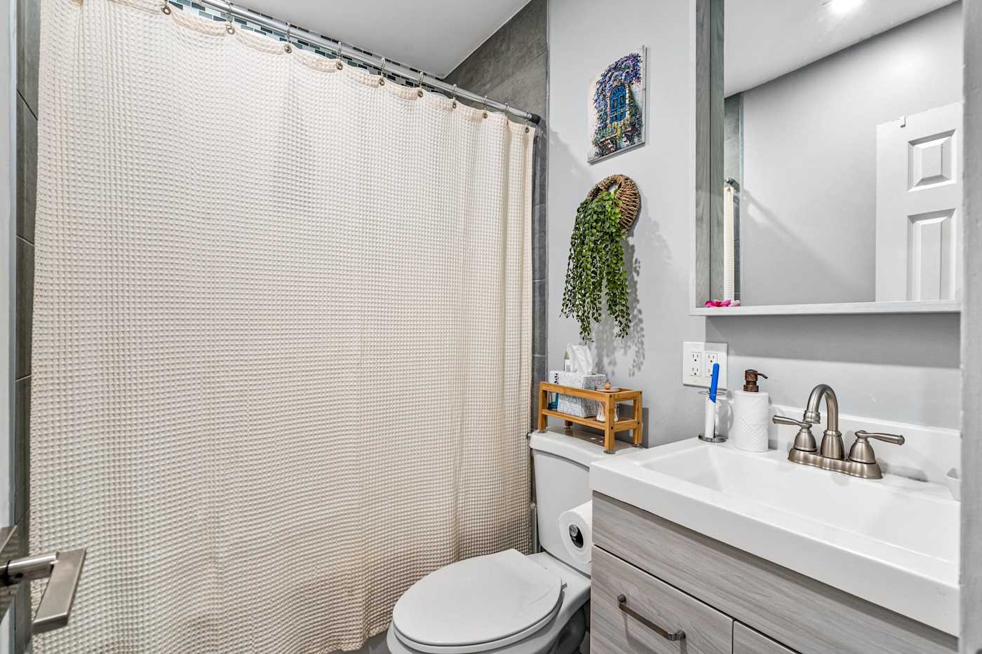 EV Retreat: The bathroom has a shower with a curtain, a toilet and a vanity