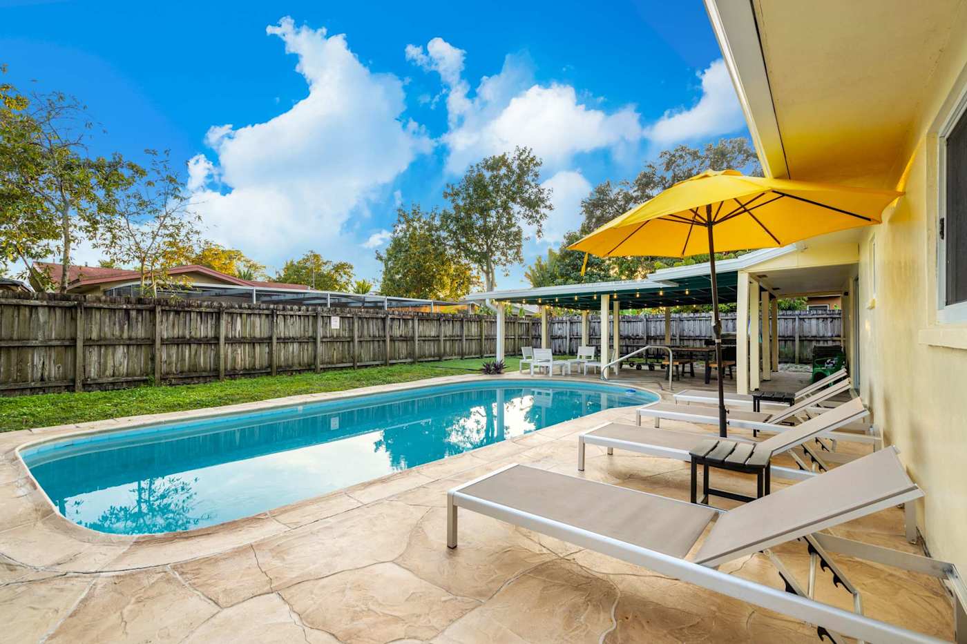 The Game House: Pool and paved deck, with loungers under the parasol