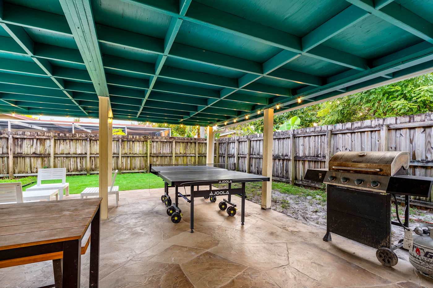 The Game House: Covered patio with ping pong and gas grill, lawn beyond
