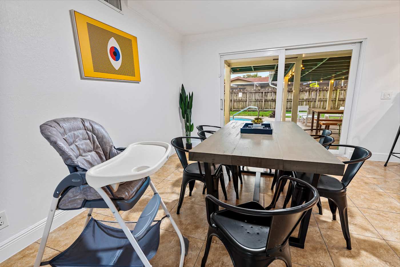 The Game House: Dining table with a high chair, and the pool through the window