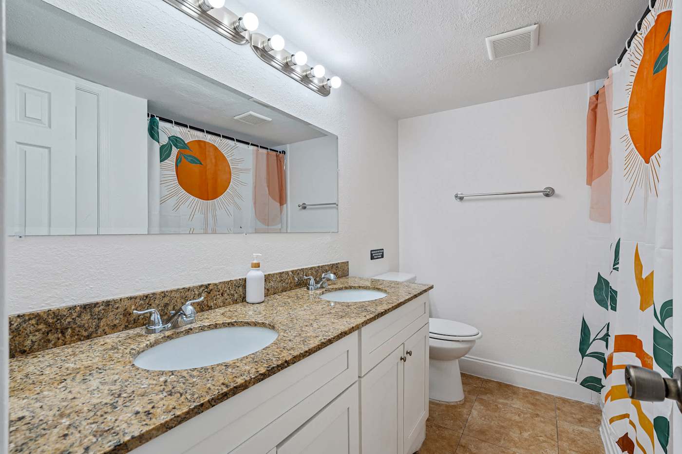 The Game House: Bathroom with double vanity, large mirror and shower over bath