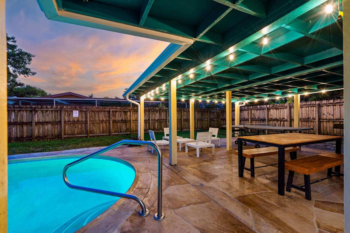 The Game House: Pool and covered patio at sunset, with the string lights on