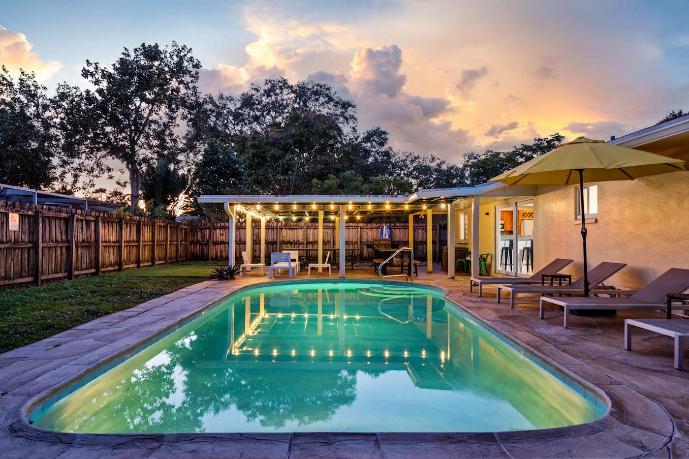 The Game House: Pool lit at dusk, with the house and patio behind