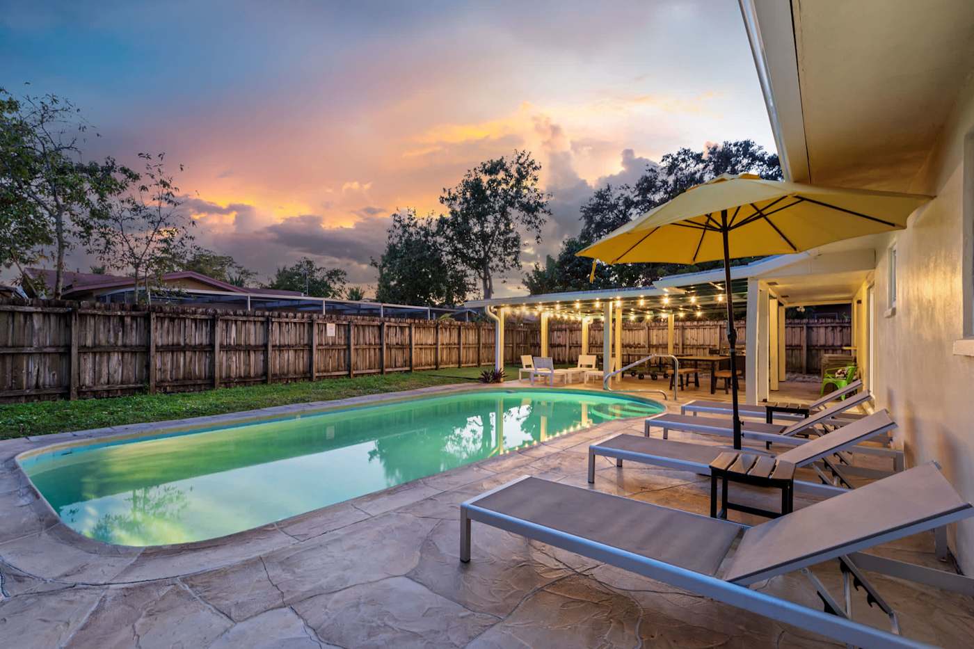 The Game House: Pool and loungers at sunset, under the parasol