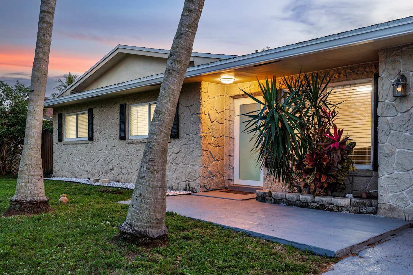 The Game House: The front entrance lit at dusk, with tropical planting