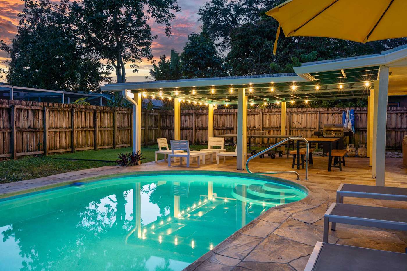 The Game House: Pool lit at dusk, with the patio and string lights behind