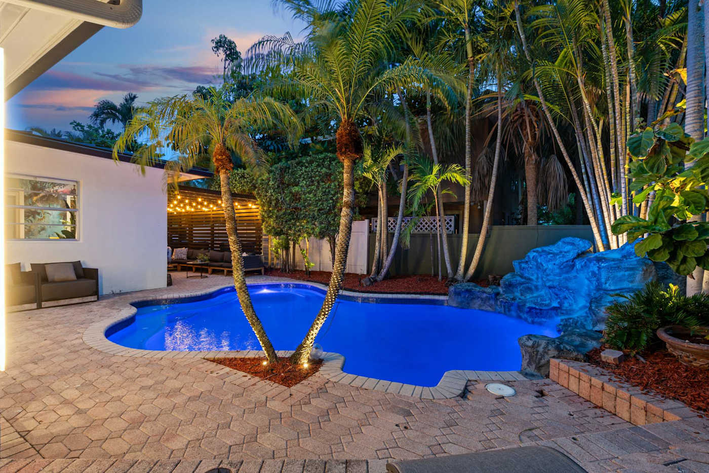 Beach Pop House: Heated pool at dusk with lit palms and lounge seating