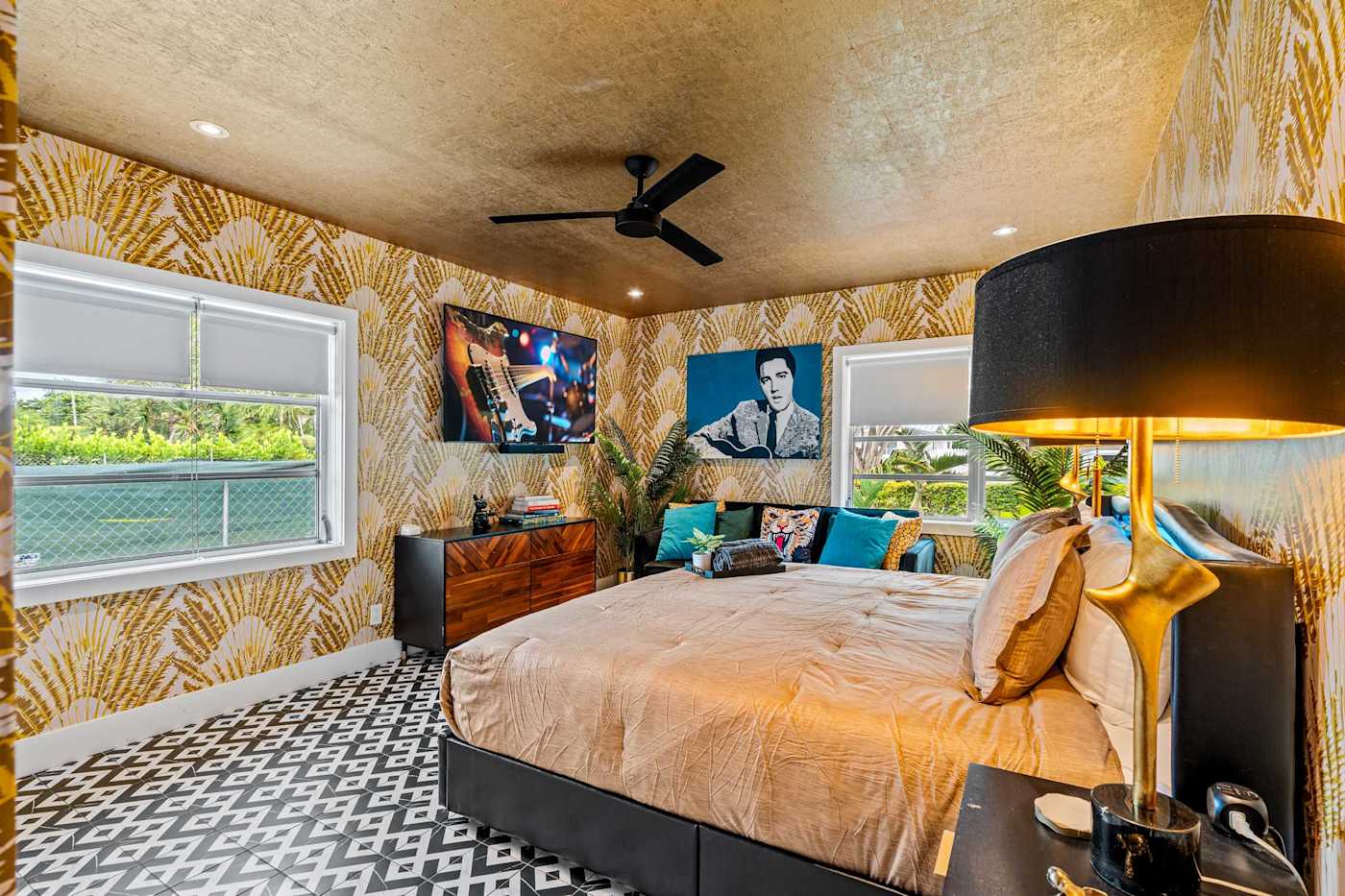 Beach Pop House: King bedroom with gold wallpaper, ceiling fan and framed art