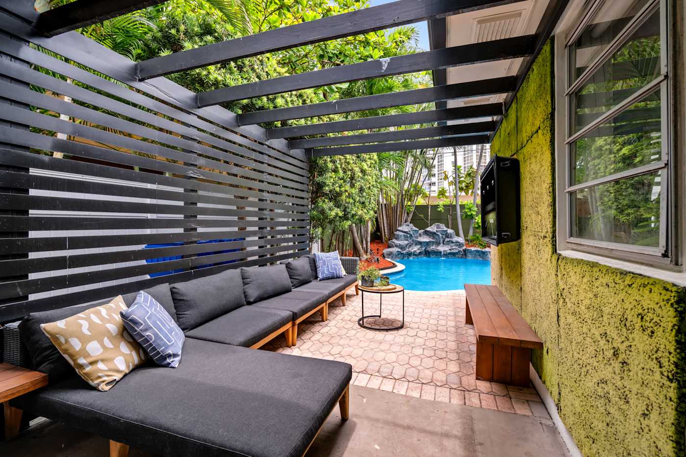 Beach Pop House: Covered outdoor lounge with sectional, opening to the pool