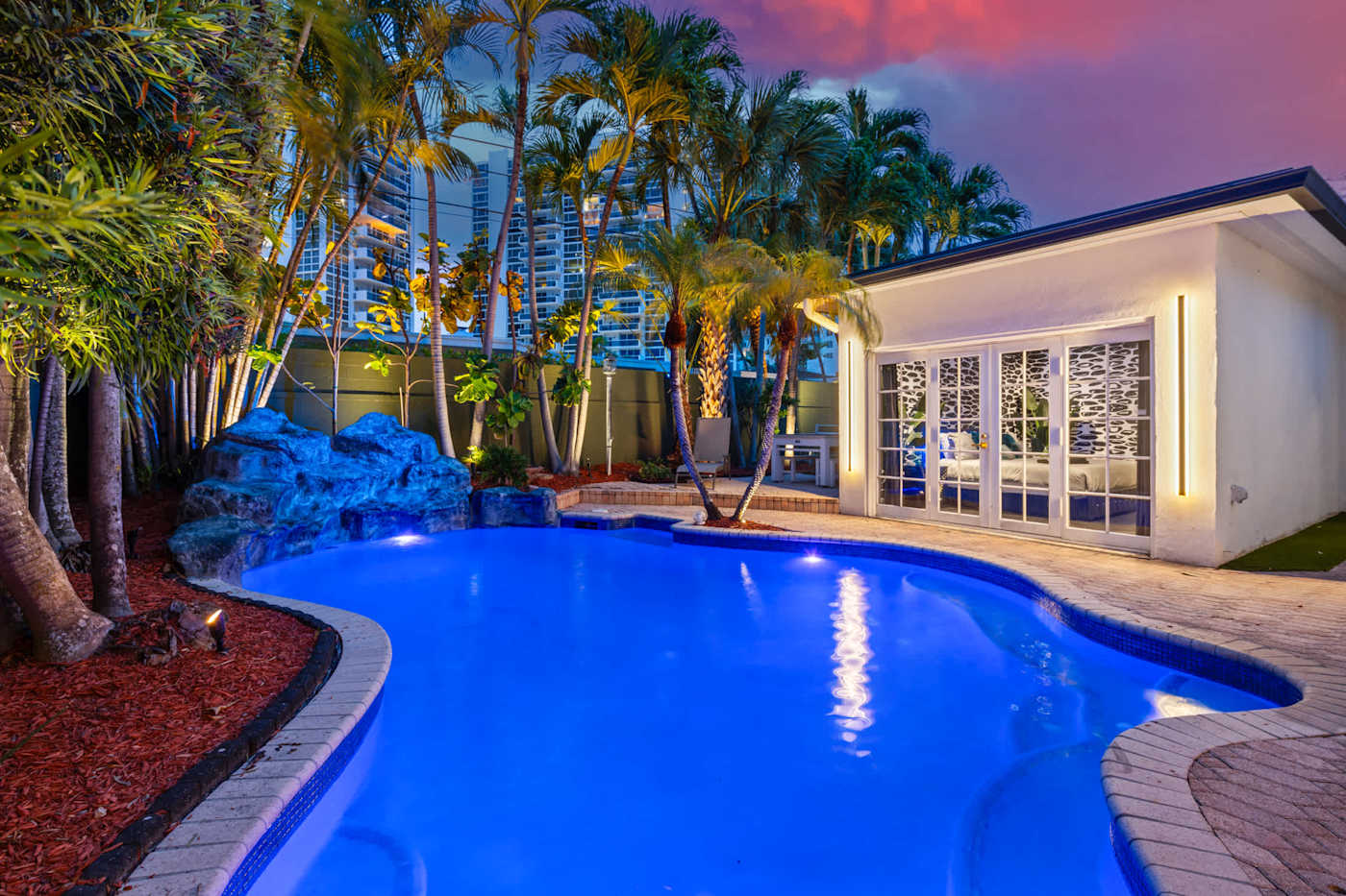 Beach Pop House: Heated pool lit blue at night, framed by palms