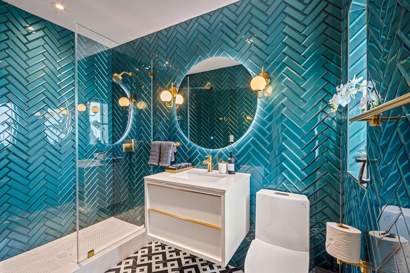 Beach Pop House: Bathroom with teal herringbone tile, round mirror and walk in shower