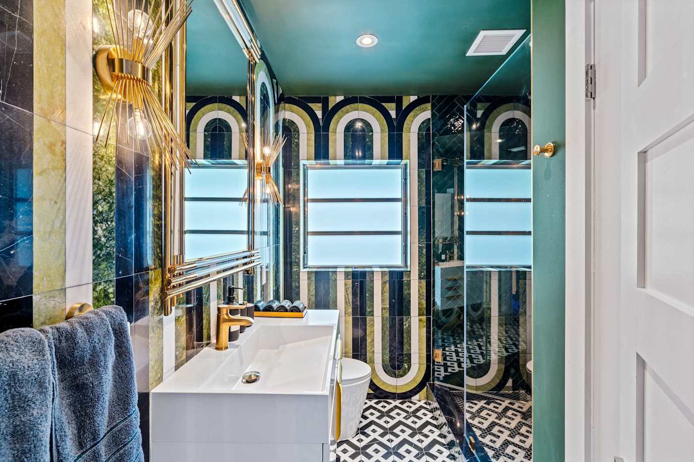 Beach Pop House: Bathroom with teal tile, arched mirrors and twin basins