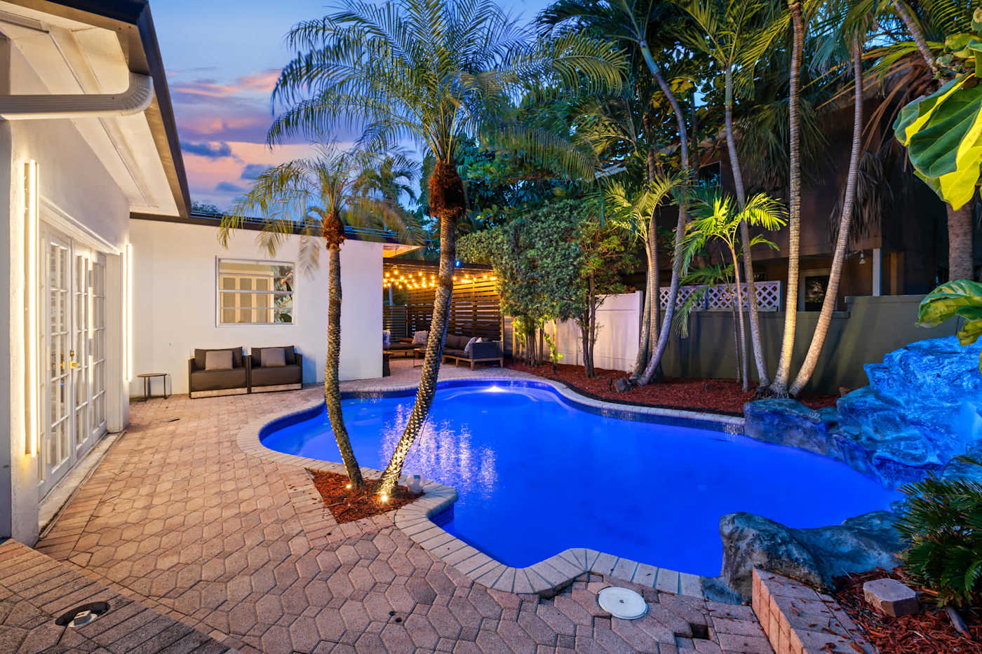 Beach Pop House: Heated pool at dusk with palms and lounge seating