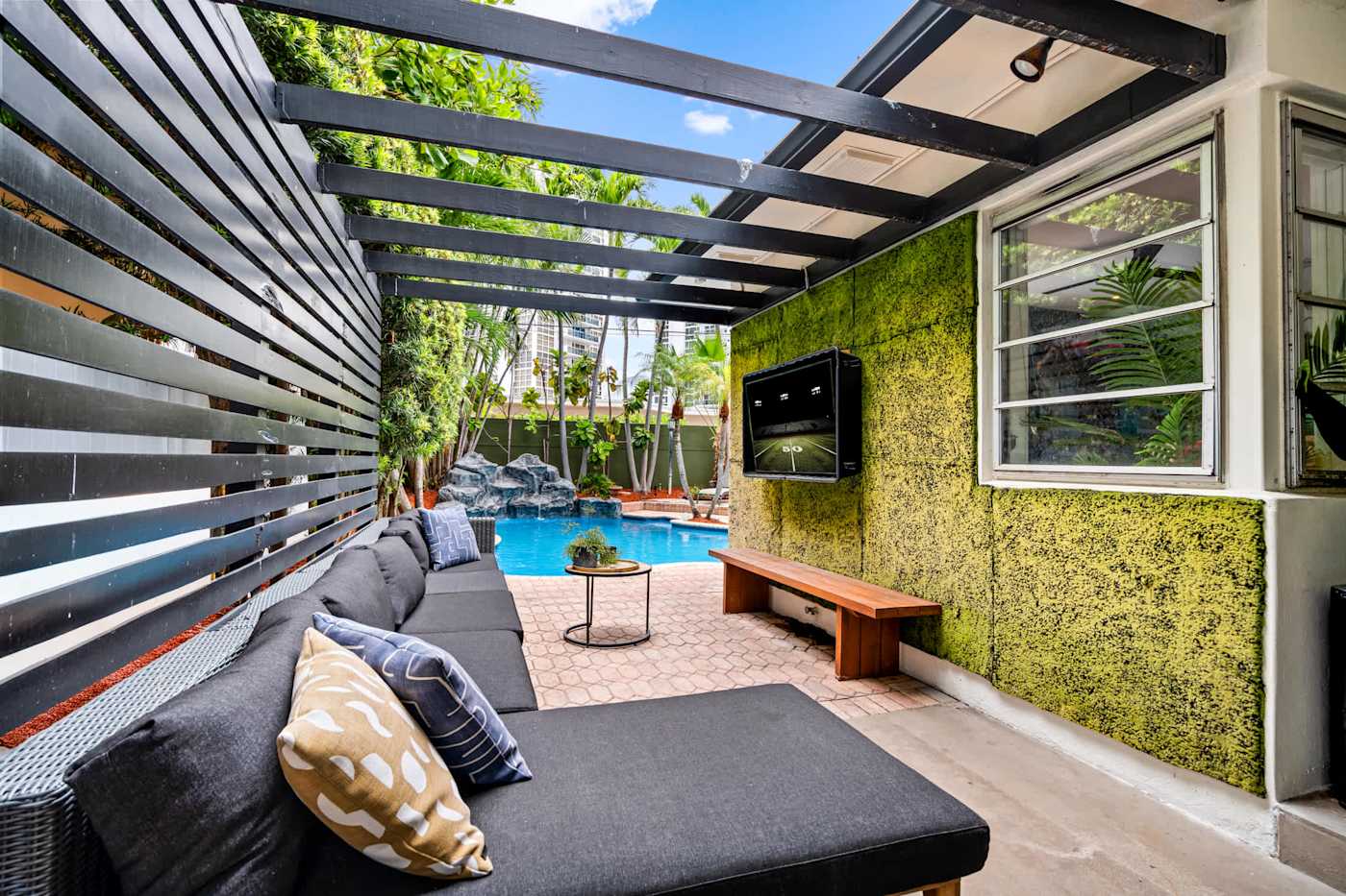 Beach Pop House: Outdoor lounge with TV, moss wall and bench seating