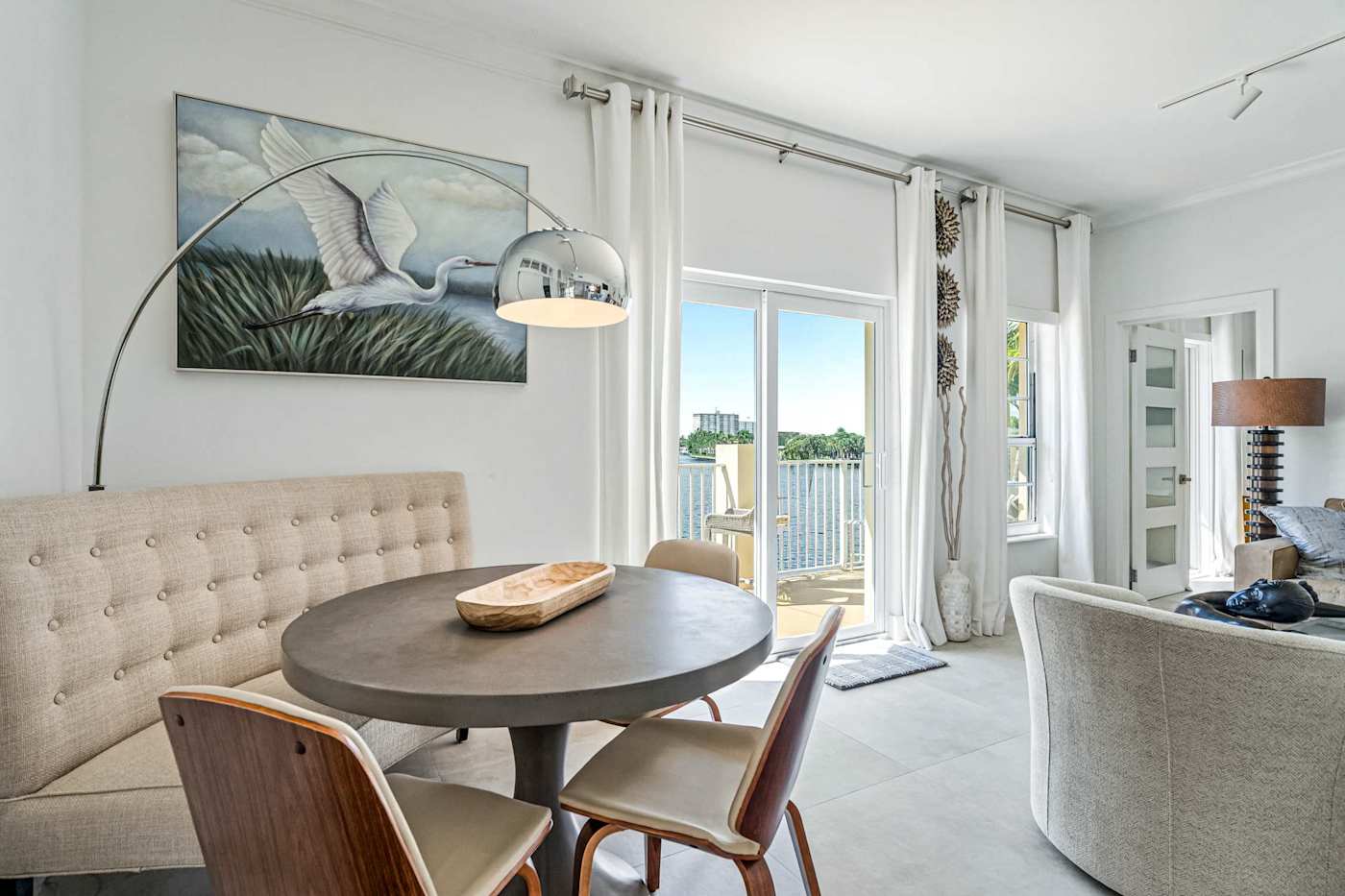 Ocean Block: A round dining table with a tufted banquette sits near the balcony doors
