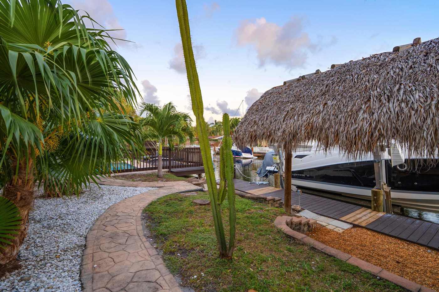 Canal House: Tiki hut and dock beside the boat, with the garden path