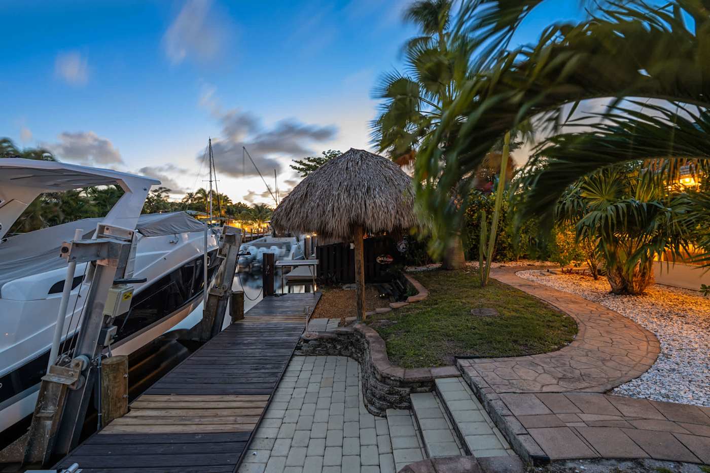 Canal House: Boat at the dock at dusk, with the tiki hut and garden