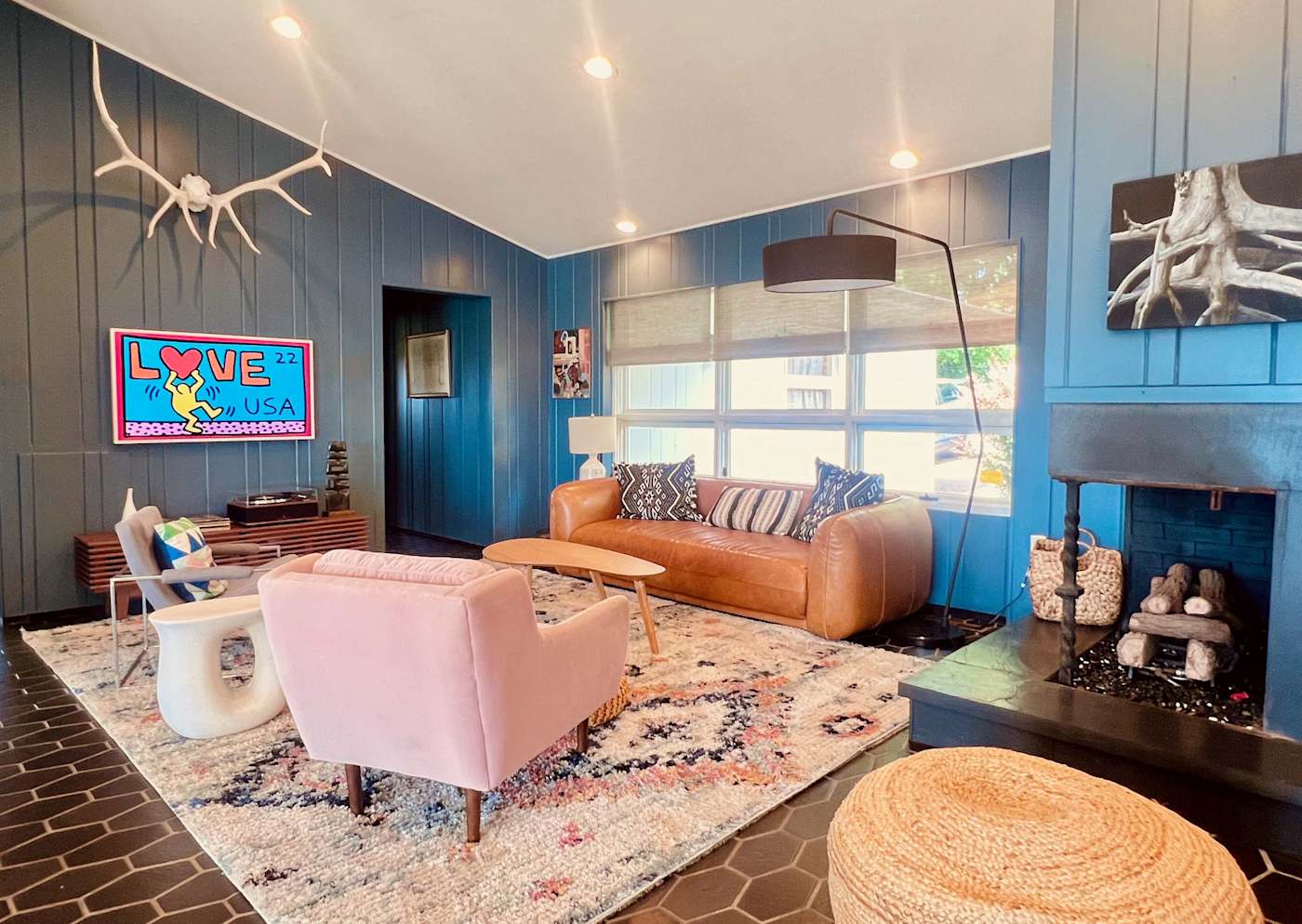 Hudson House: Den seating with pink armchair, leather sofa and fireplace