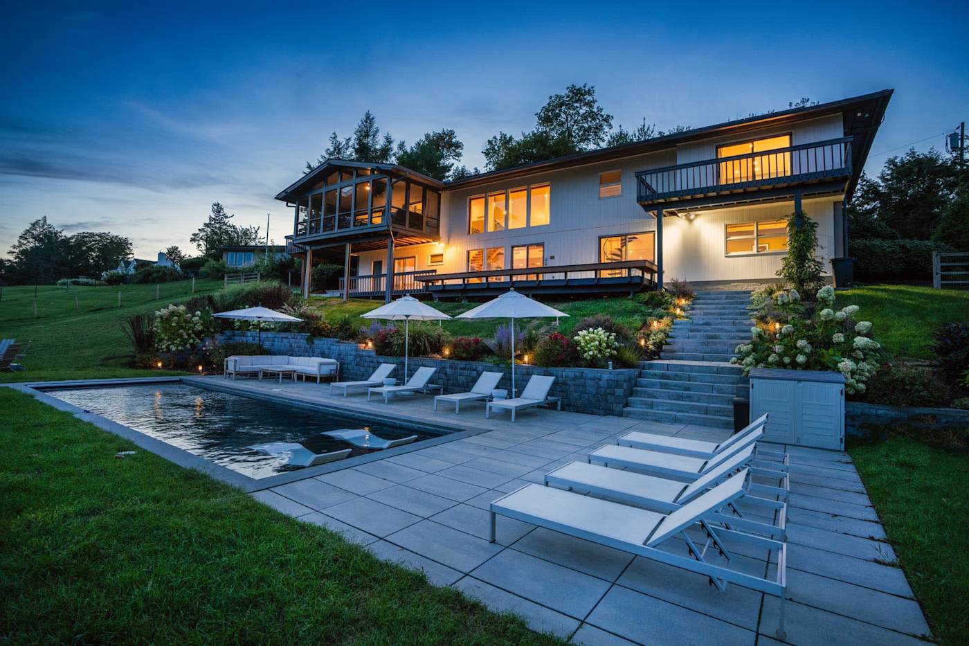 Hudson House: Back of the house and pool patio lit up at twilight