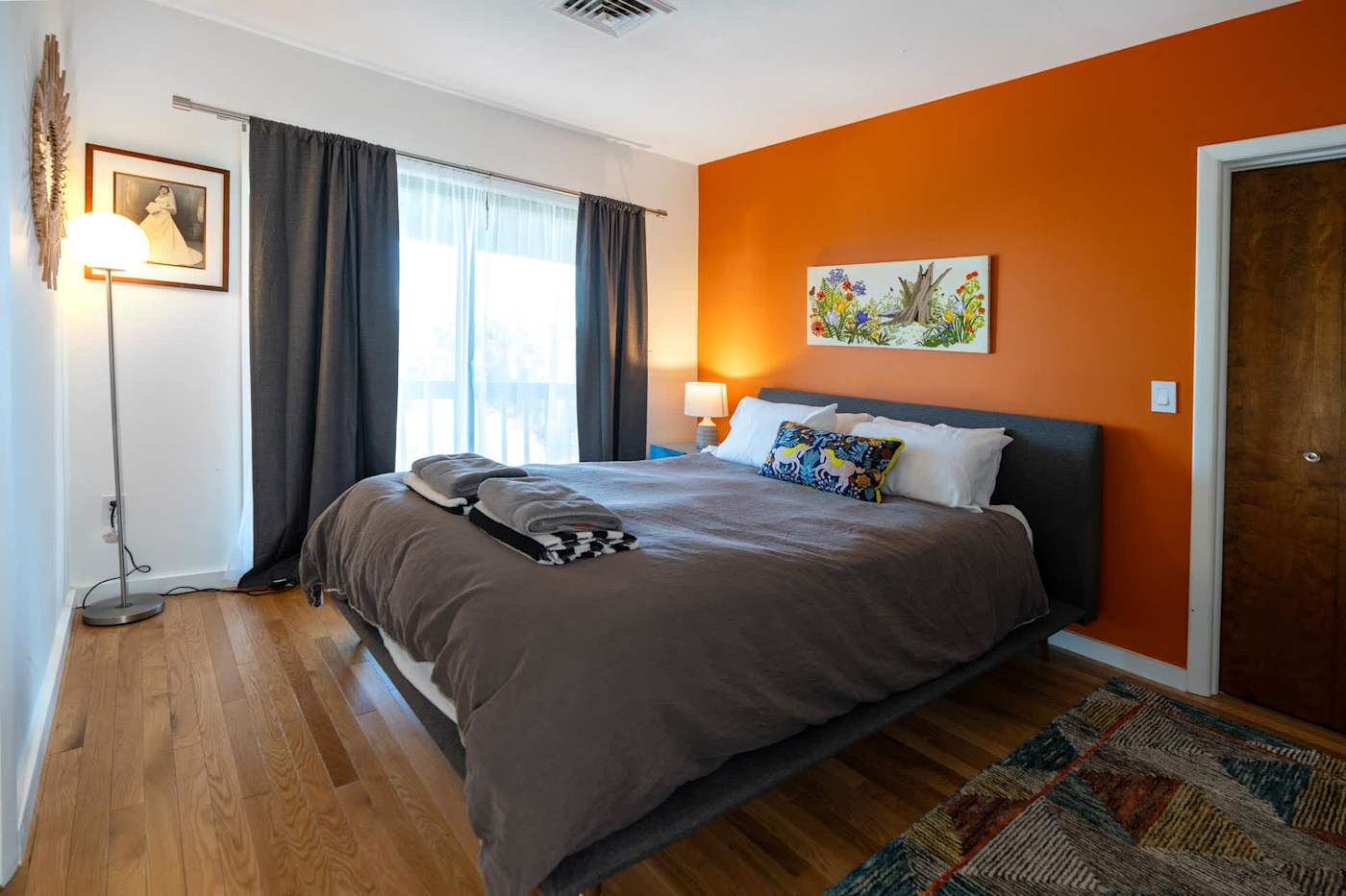Hudson House: Orange-walled bedroom with upholstered bed and blackout curtains