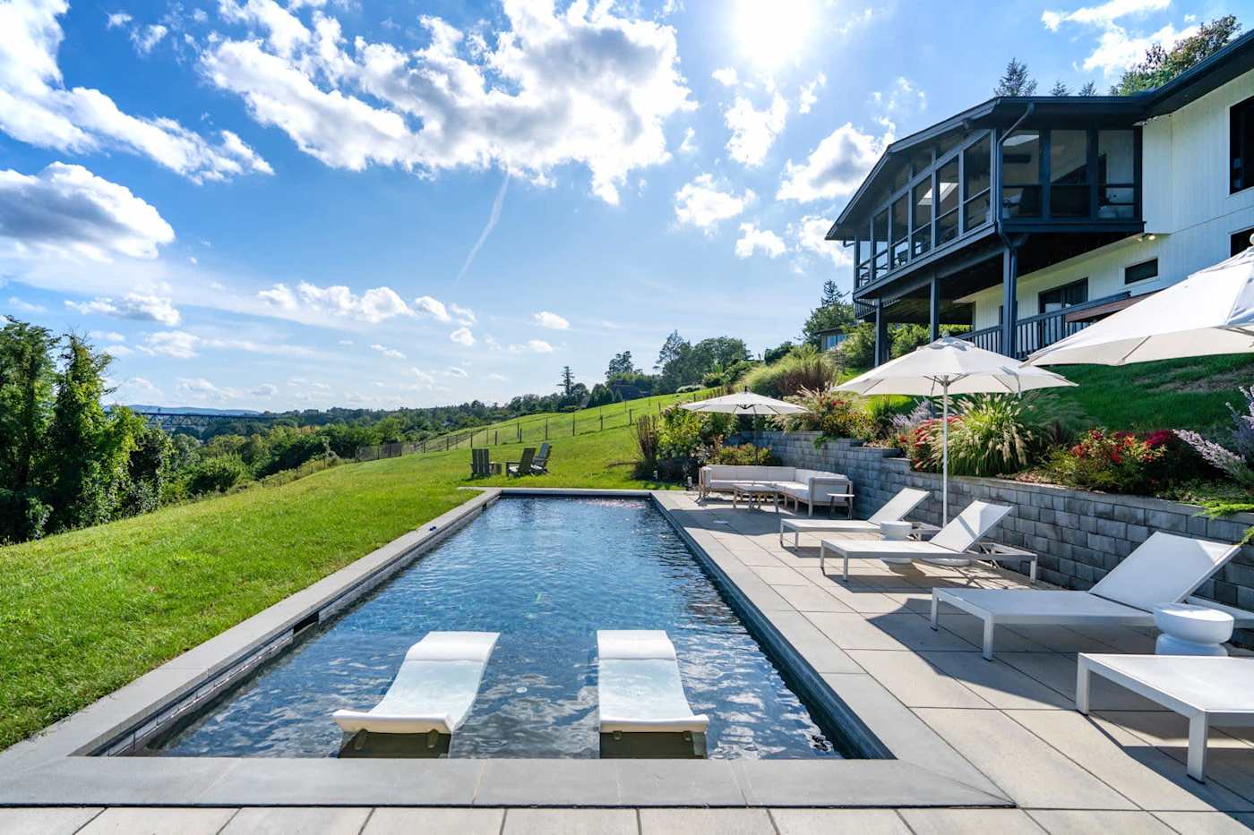 Hudson House: Long heated pool beside the lawn with patio chaises