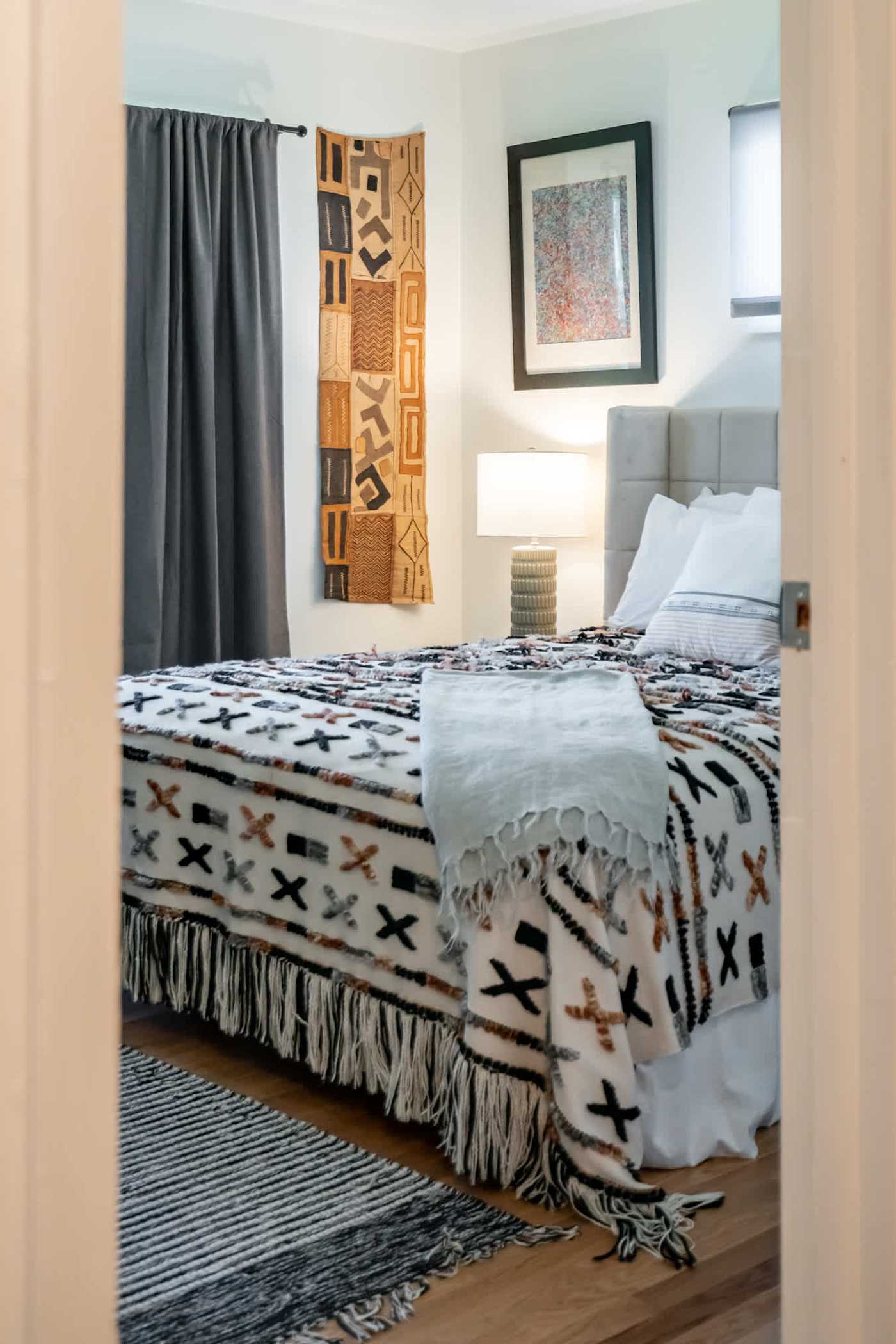 Hudson House: Bedroom with tufted headboard and patterned throw, seen from the door