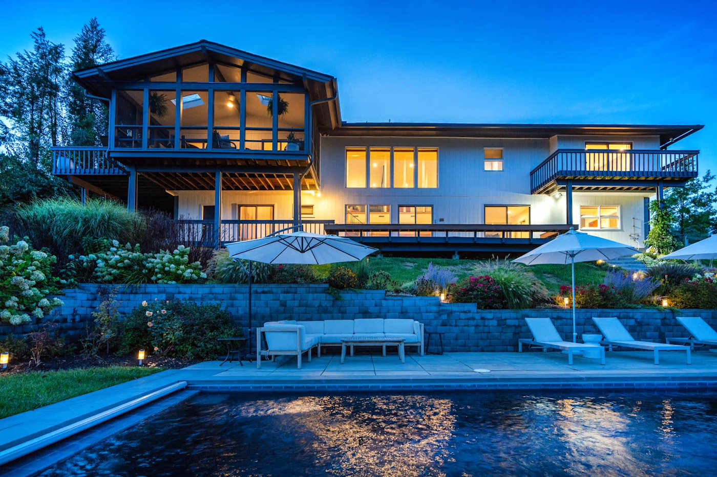 Hudson House: Back of the house at dusk with the heated pool and screened porch