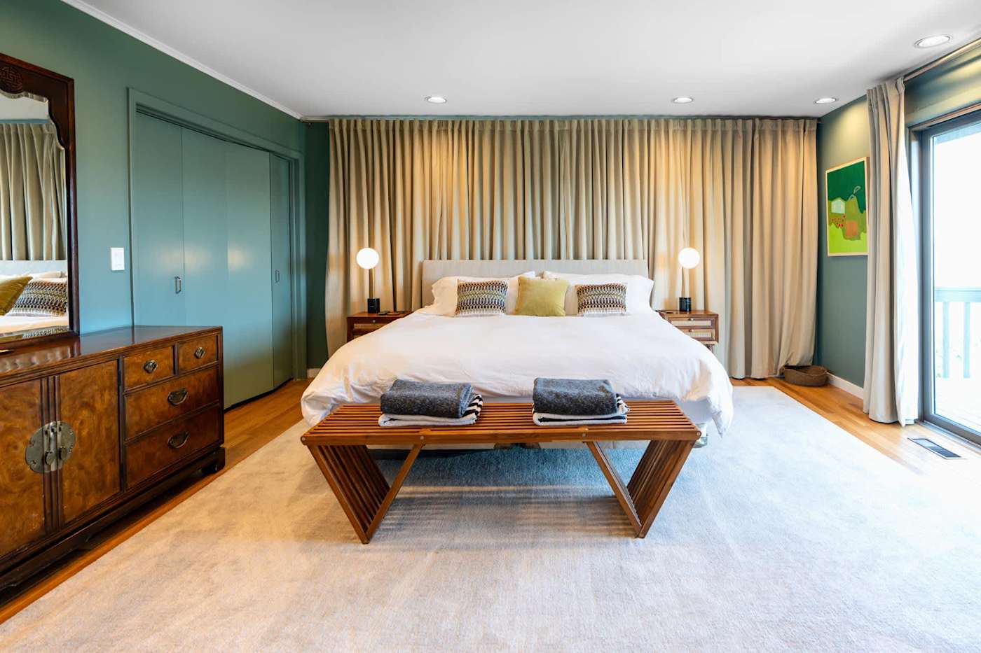 Hudson House: Green-walled bedroom with large bed, dresser and balcony door