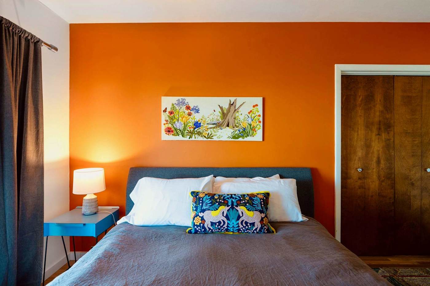Hudson House: Orange-walled bedroom headboard with floral print and nightstand