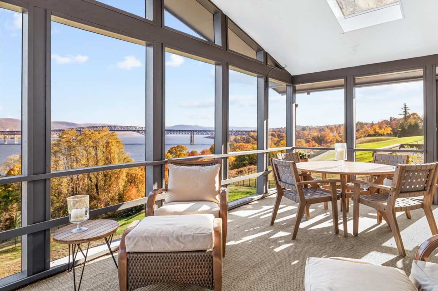 Hudson House: Screened porch in autumn with dining table and river views