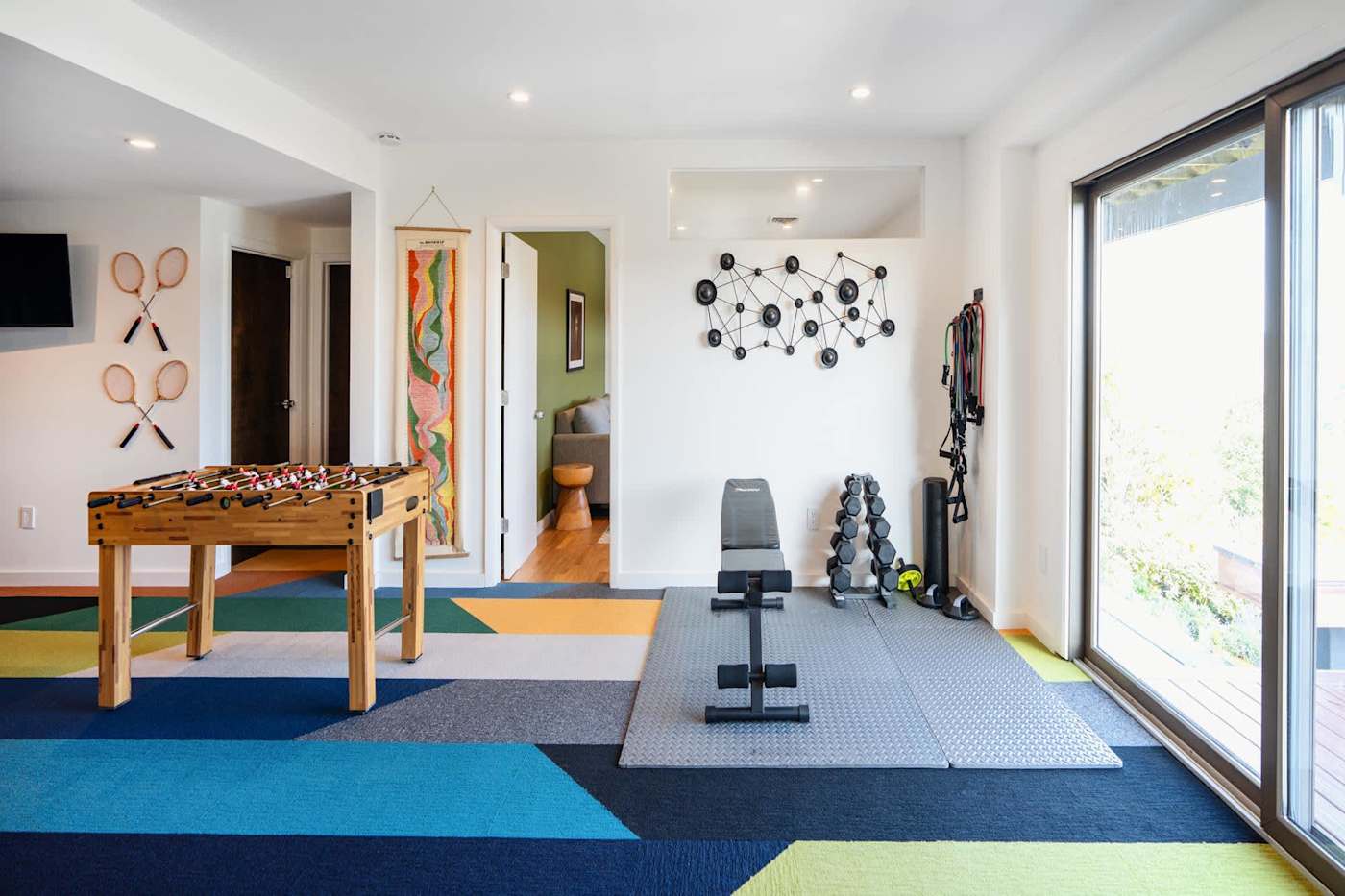 Hudson House: Exercise area with weight bench and dumbbells beside the game room