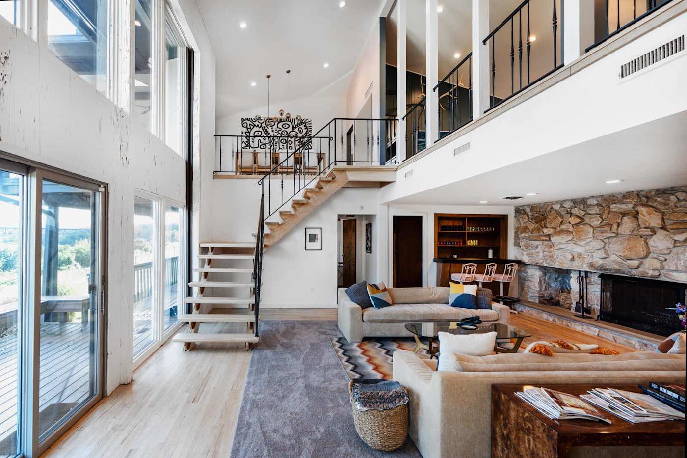 Hudson House: Double-height living room with stone fireplace and floating staircase