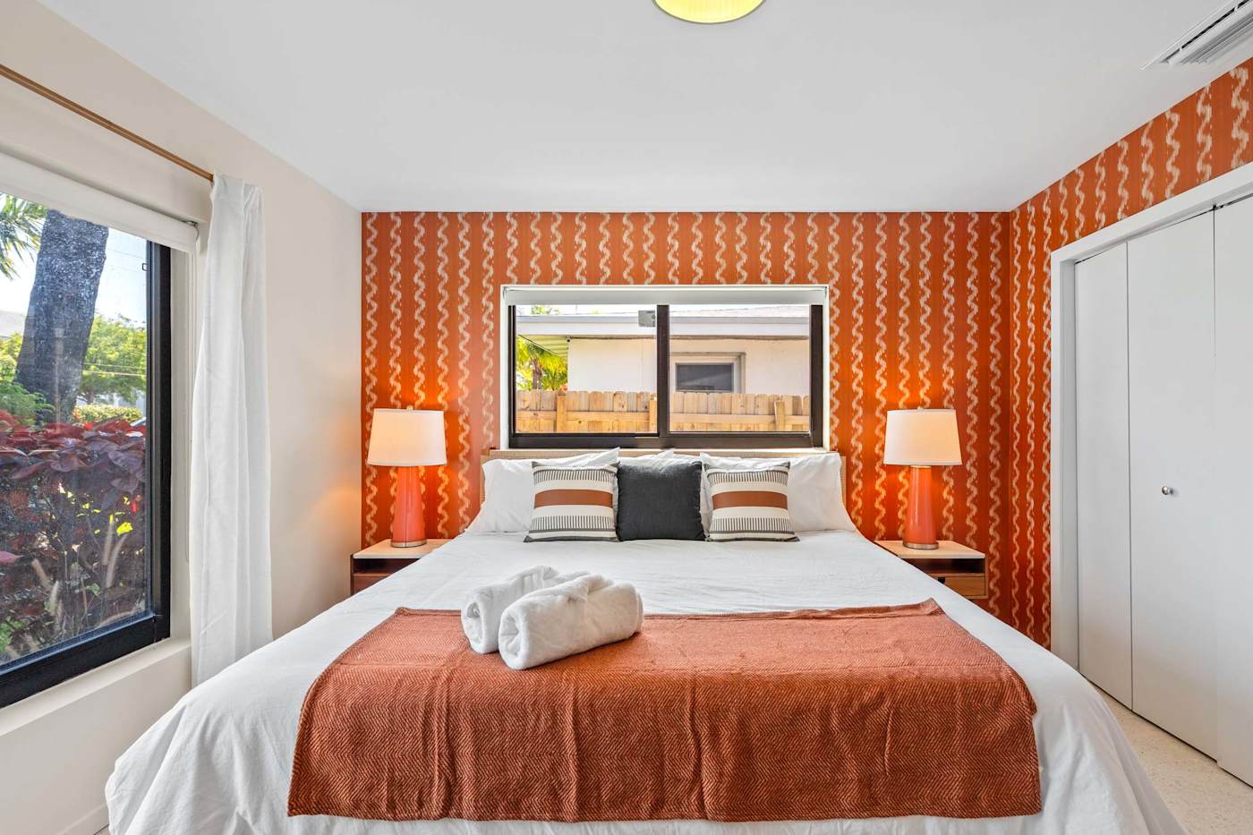 Mangrove Manor: King bedroom with orange patterned feature wall and bedside lamps
