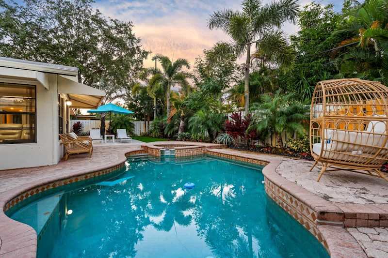 Gardens By The Sea: Pool and hanging egg chair, framed by palms at dusk
