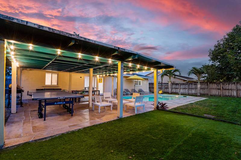 The Game House: Covered patio with ping pong and seating, lit at sunset
