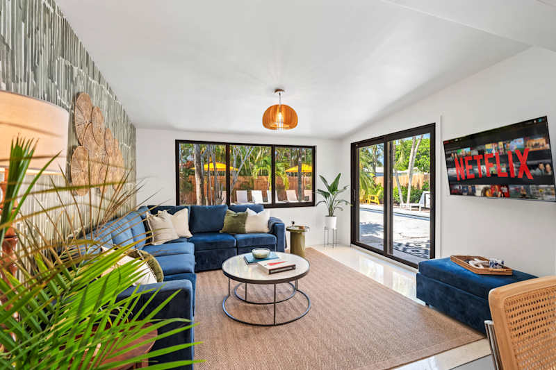 Mangrove Manor: Living room with velvet sectional, smart TV and sliding doors onto the pool deck