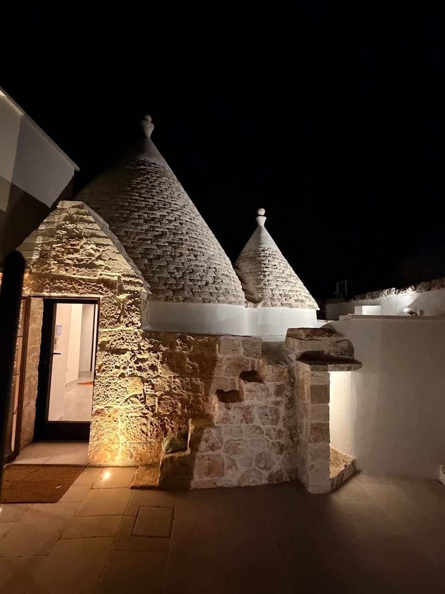 Trullo Ostro: Trullo entrance with lit stone walls at night