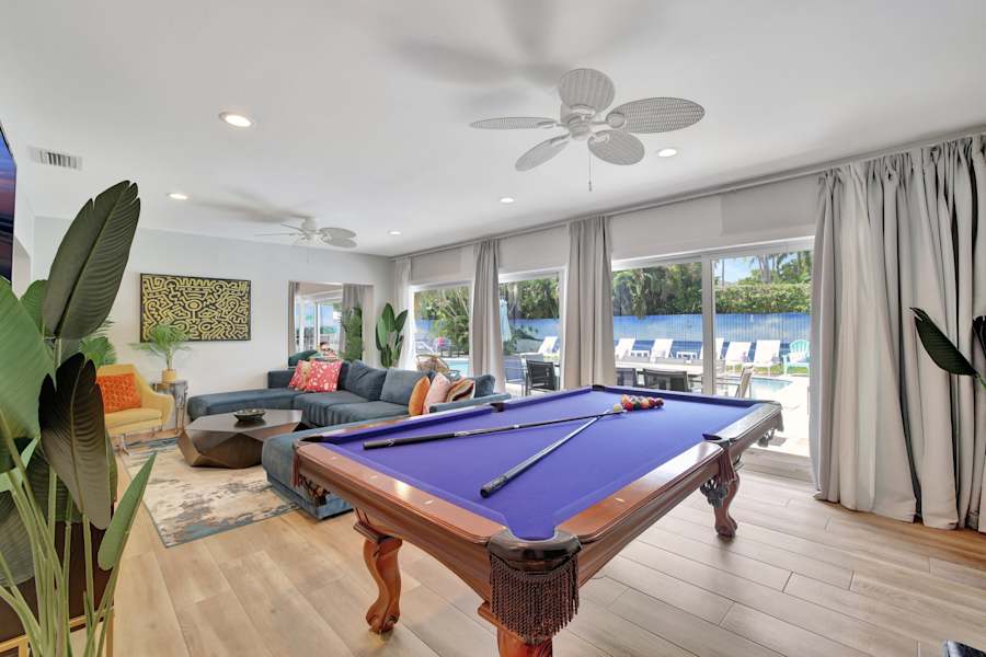 6 Bed Beach House: Pool table in the open living space, with the pool through the windows
