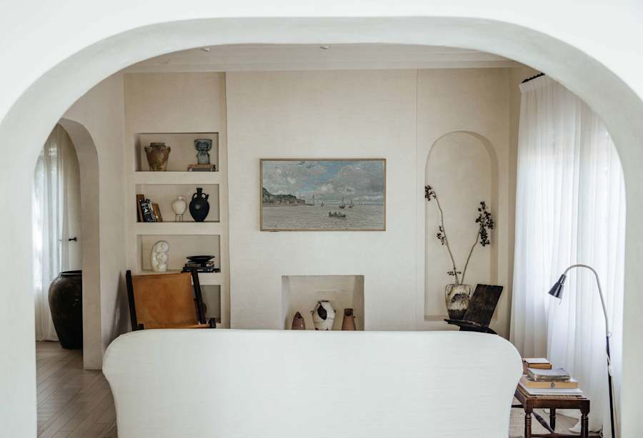 Sol y Sombra: Living room featuring a frame TV, custom couch, vintage book shelves and arched hallway