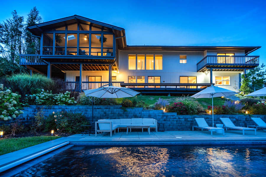 Hudson House: Back of the house at dusk with the heated pool and screened porch