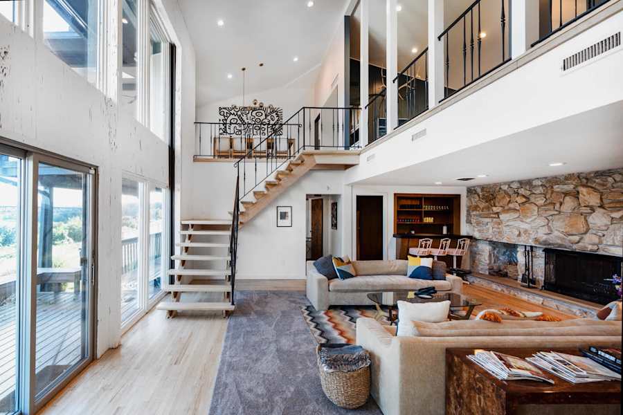 Hudson House: Double-height living room with stone fireplace and floating staircase
